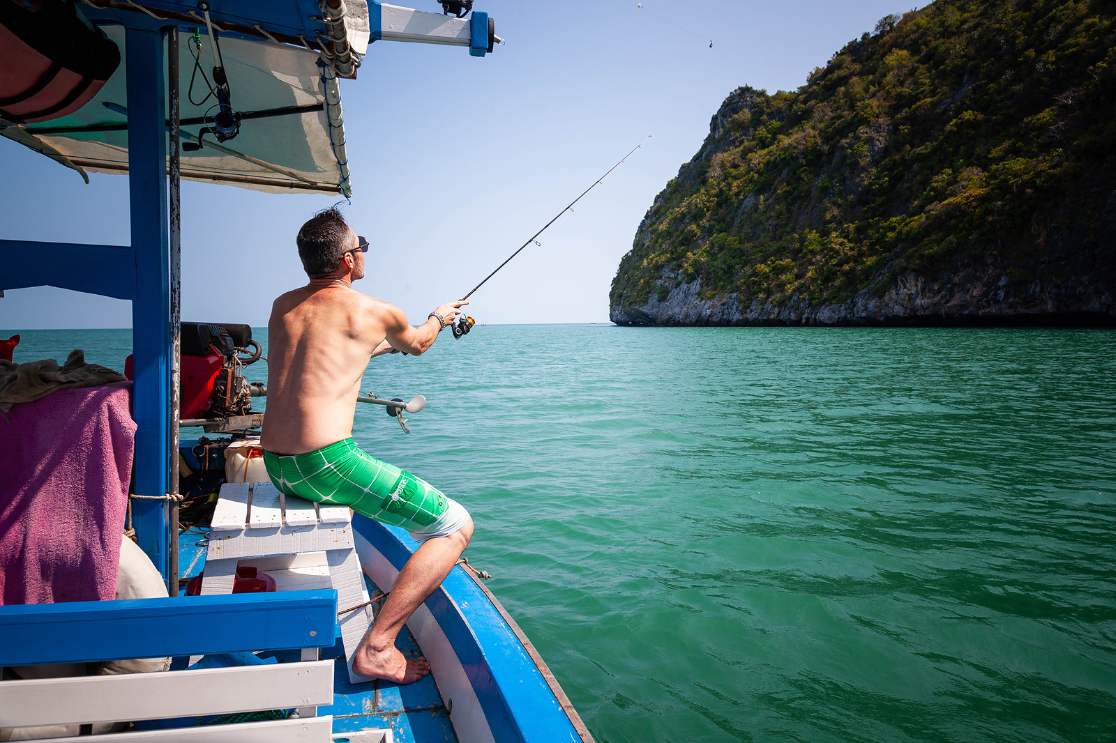 "Fisherman casting a line at Tao Rehab Thailand, surrounded by tranquil waters."